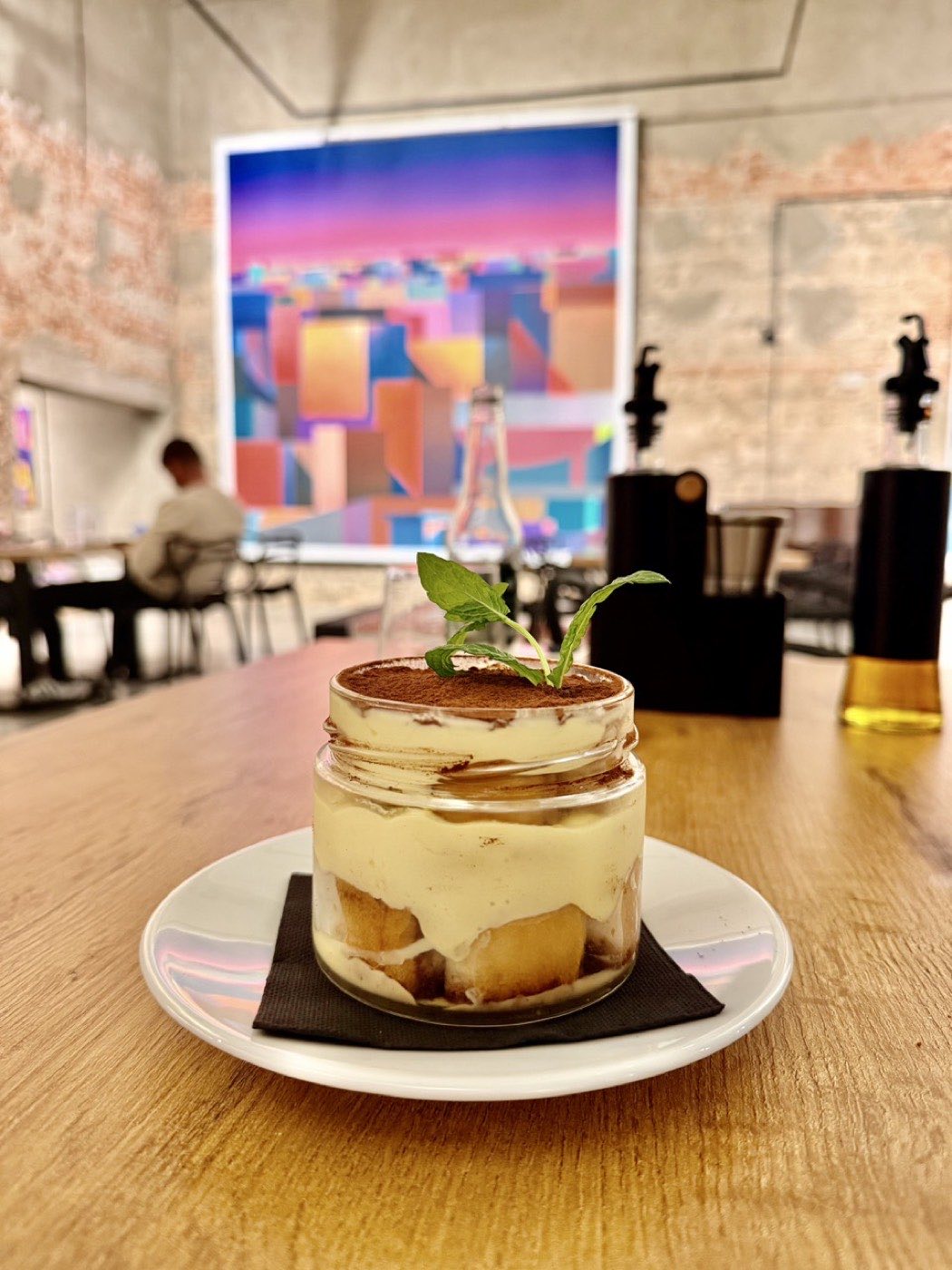 Tiramisu w szklanym słoiku, gruba warstwa kremu mascarpone, kakao i listki mięty